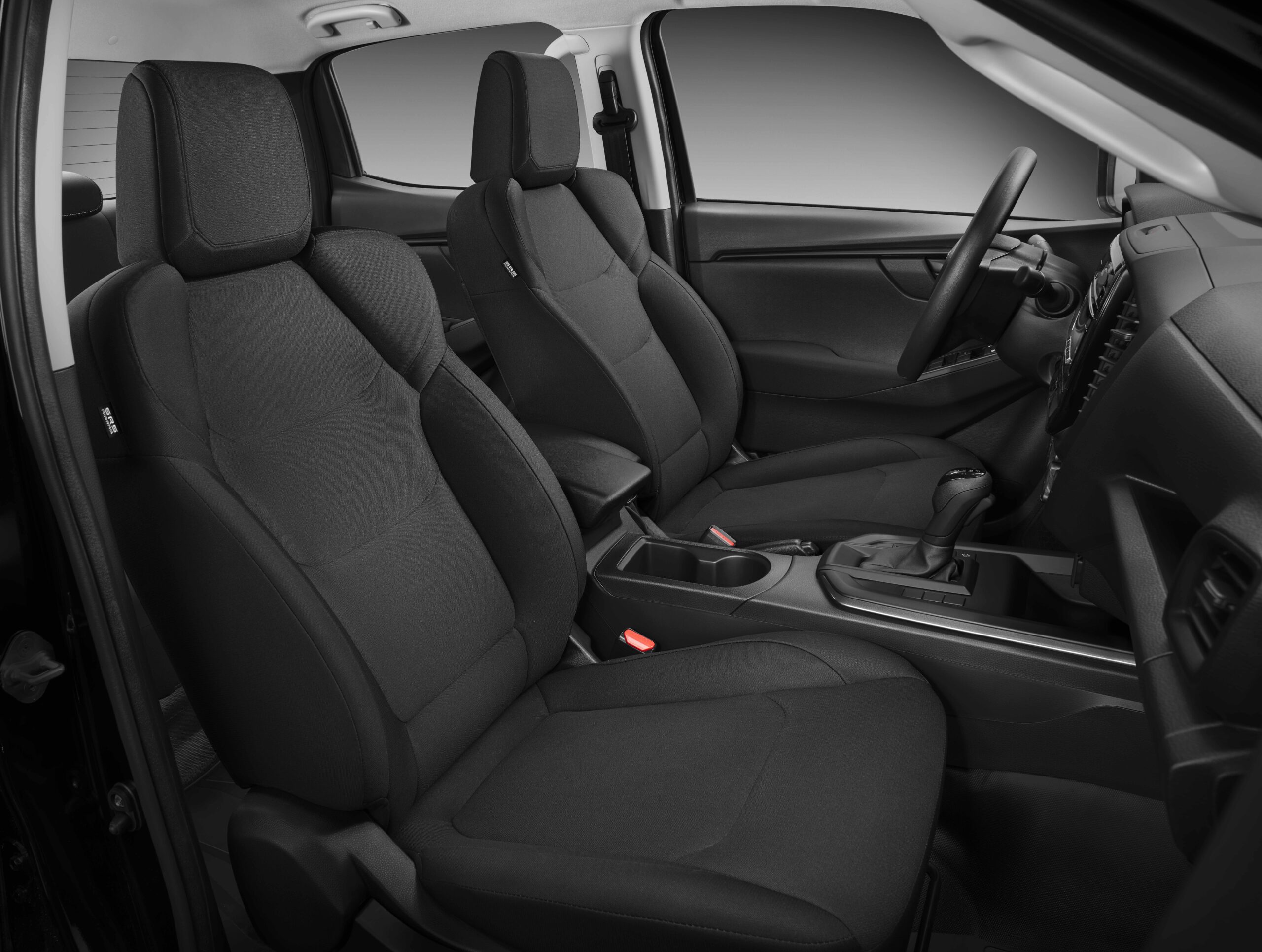 Intérieur sombre de véhicule, sièges en tissu noir et console centrale avec mention SRS Airbag.